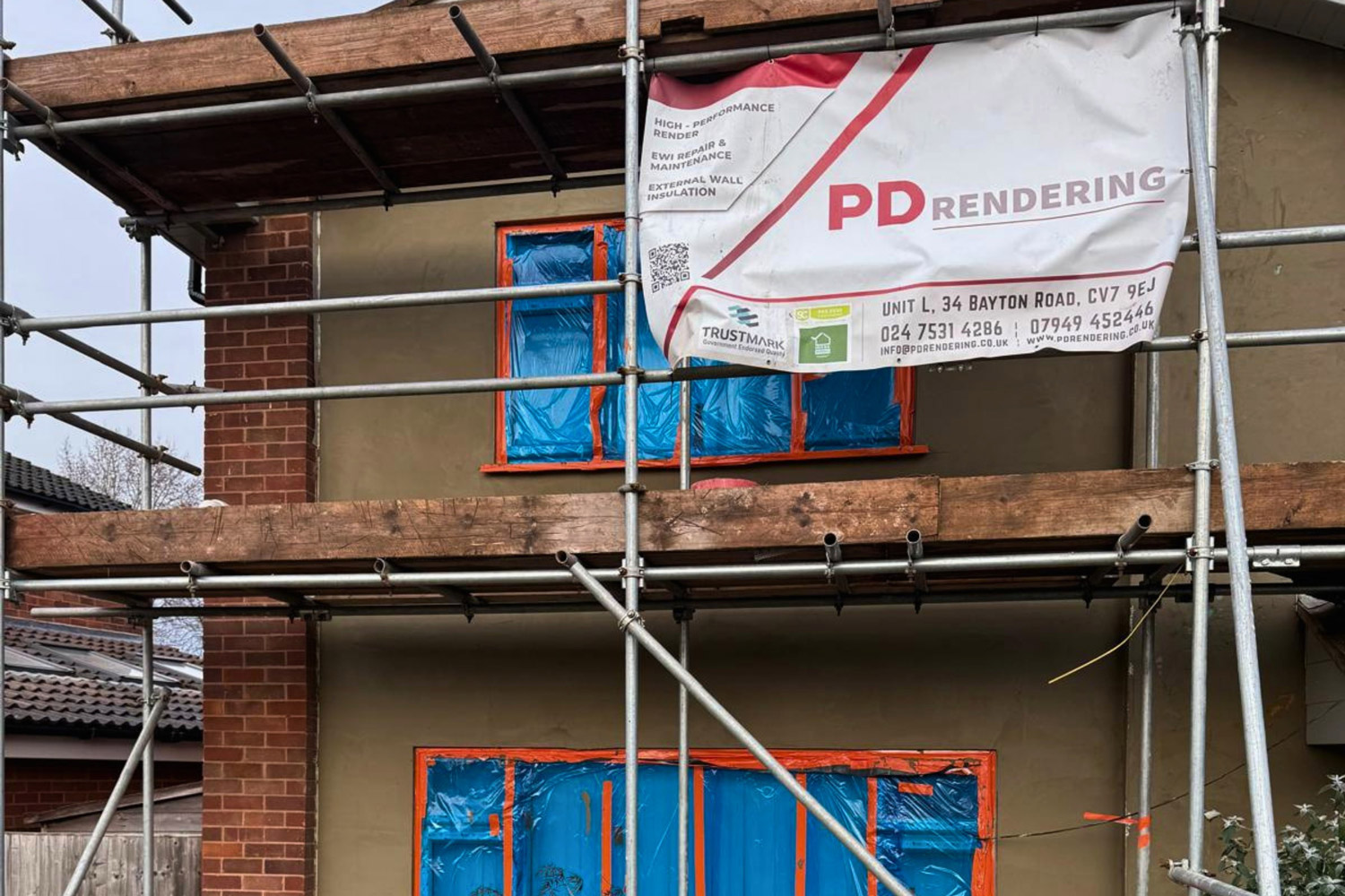 A UK house covered in scaffolding during the application of a polymer-modified basecoat and fibreglass mesh by PD Rendering.
