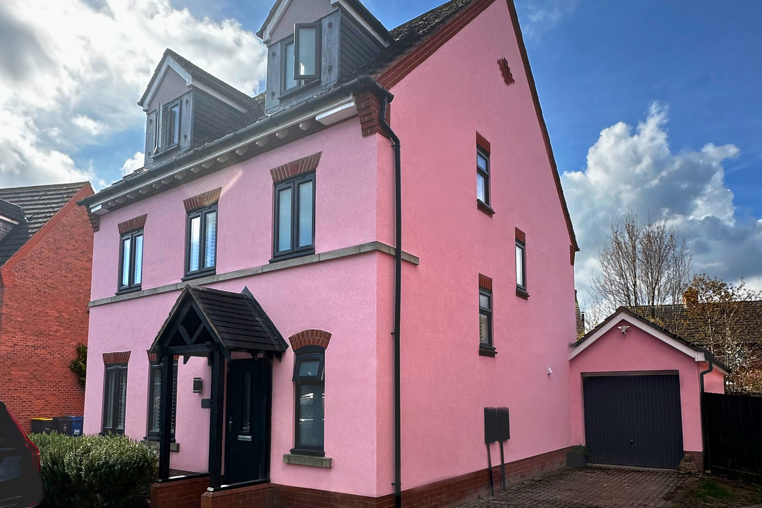 A large detached UK house beautifully finished in a bold, UV-stable pink silicone render by PD Rendering, showcasing the vast colour options available.