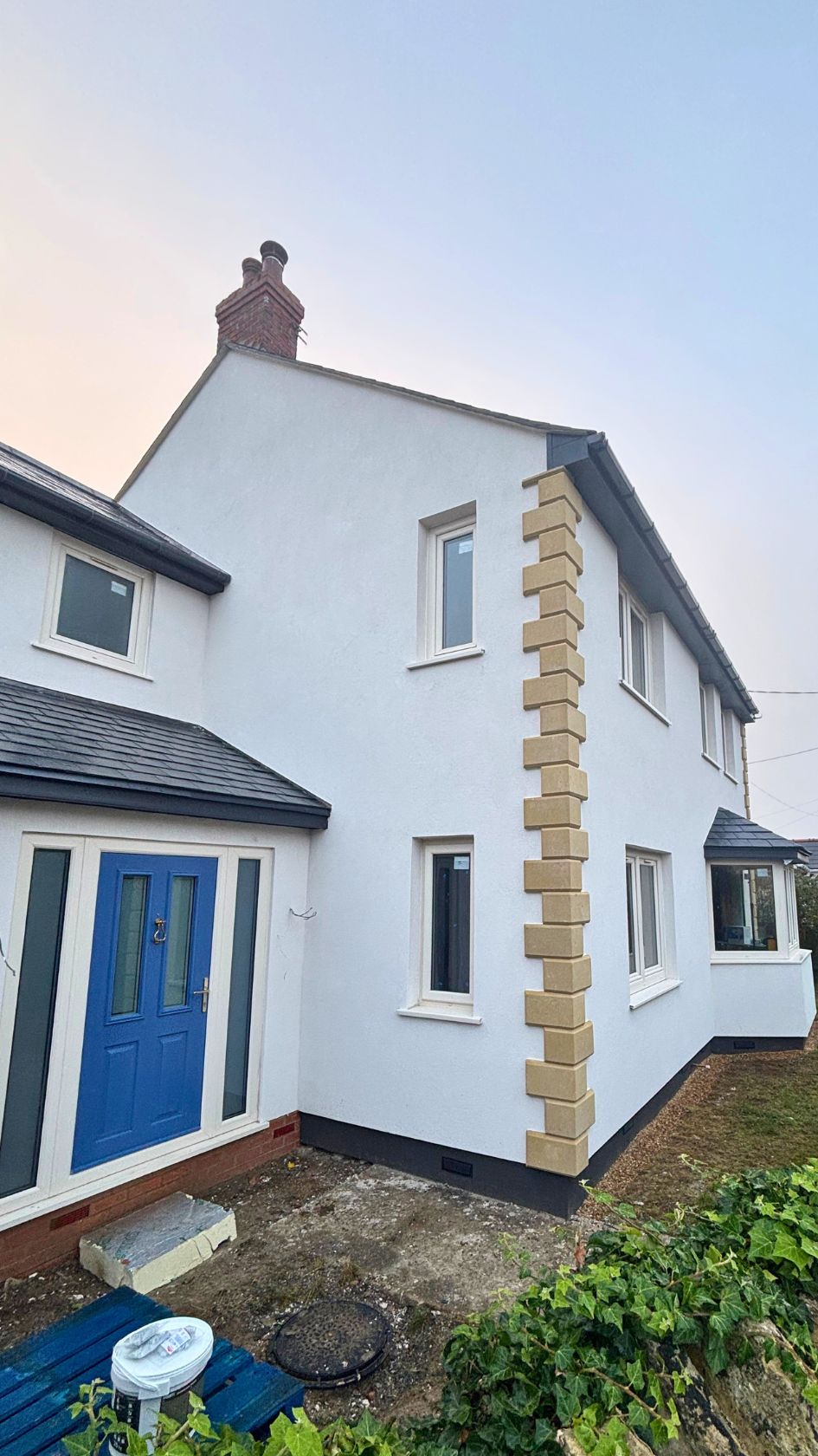Home exterior upgraded with a crisp white silicone render system over external wall insulation and decorative corner quoins.