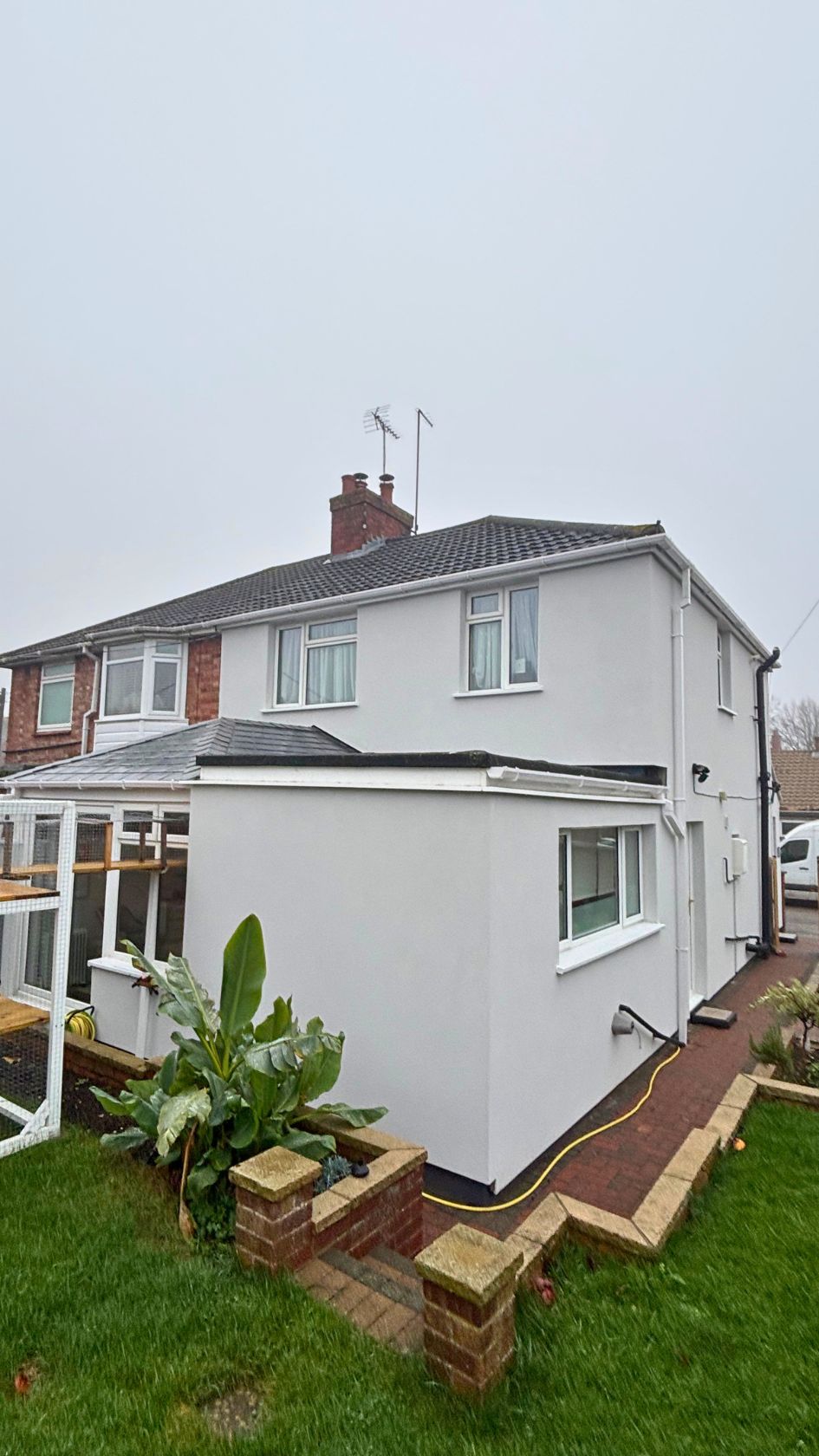 White self-cleaning silicone render applied to the exterior walls and rear extension of a residential property.