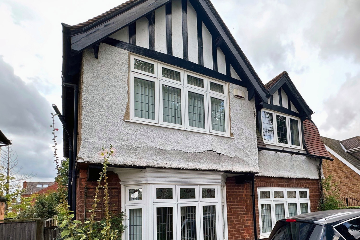 A traditional UK property with severe horizontal cracks and blown render on the exterior facade, requiring professional repair and restoration by PD Rendering.