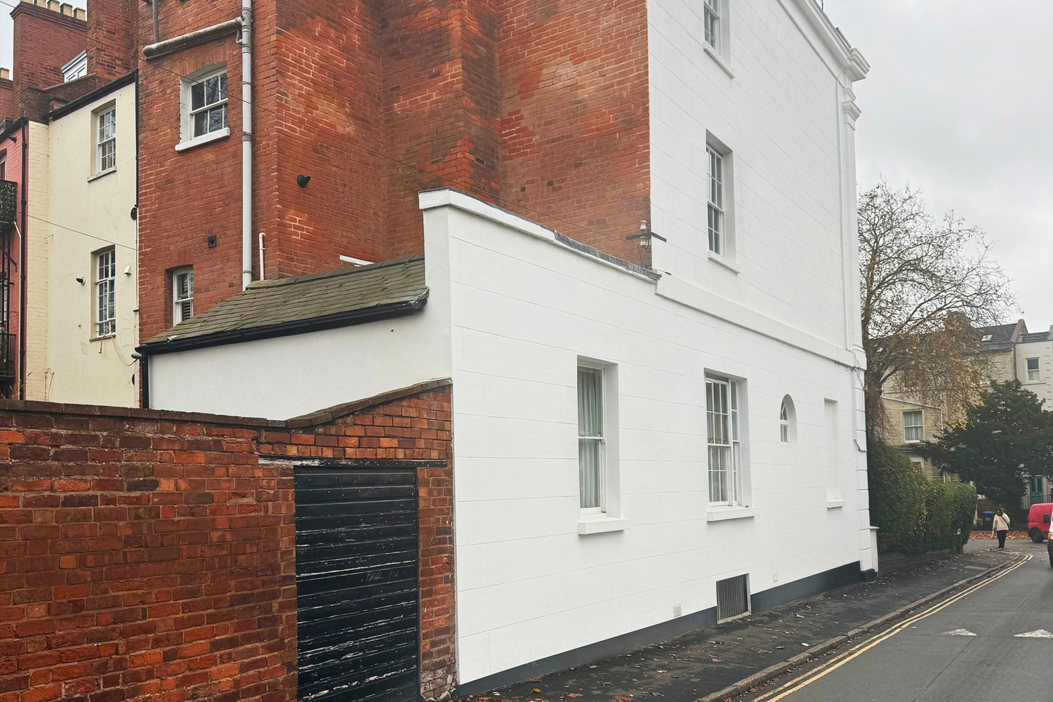 A historic multi-storey UK property featuring a newly applied, highly breathable white lime render by PD Rendering, beautifully contrasting with the original red brickwork.